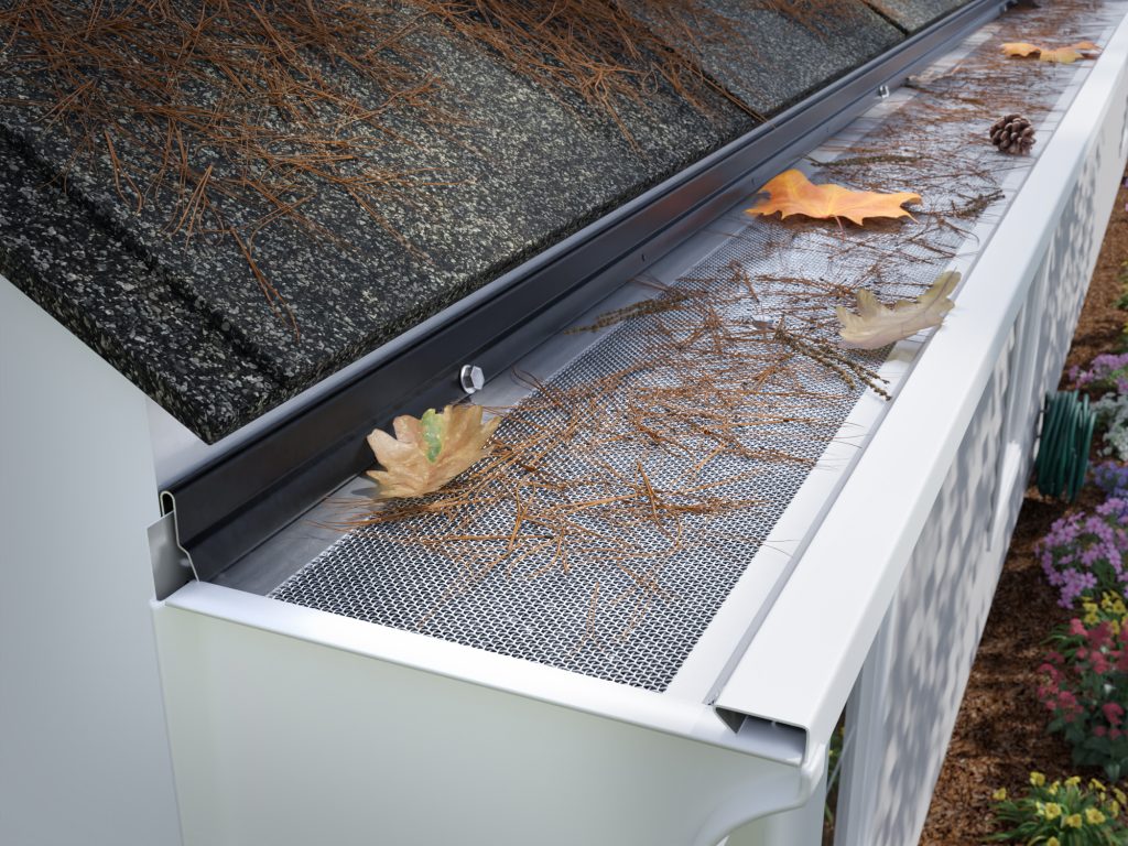 Sasquatch fine debris filter screen with pine needles caught on top of the aluminum cover &mdash; keeping the gutter channel clear underneath.