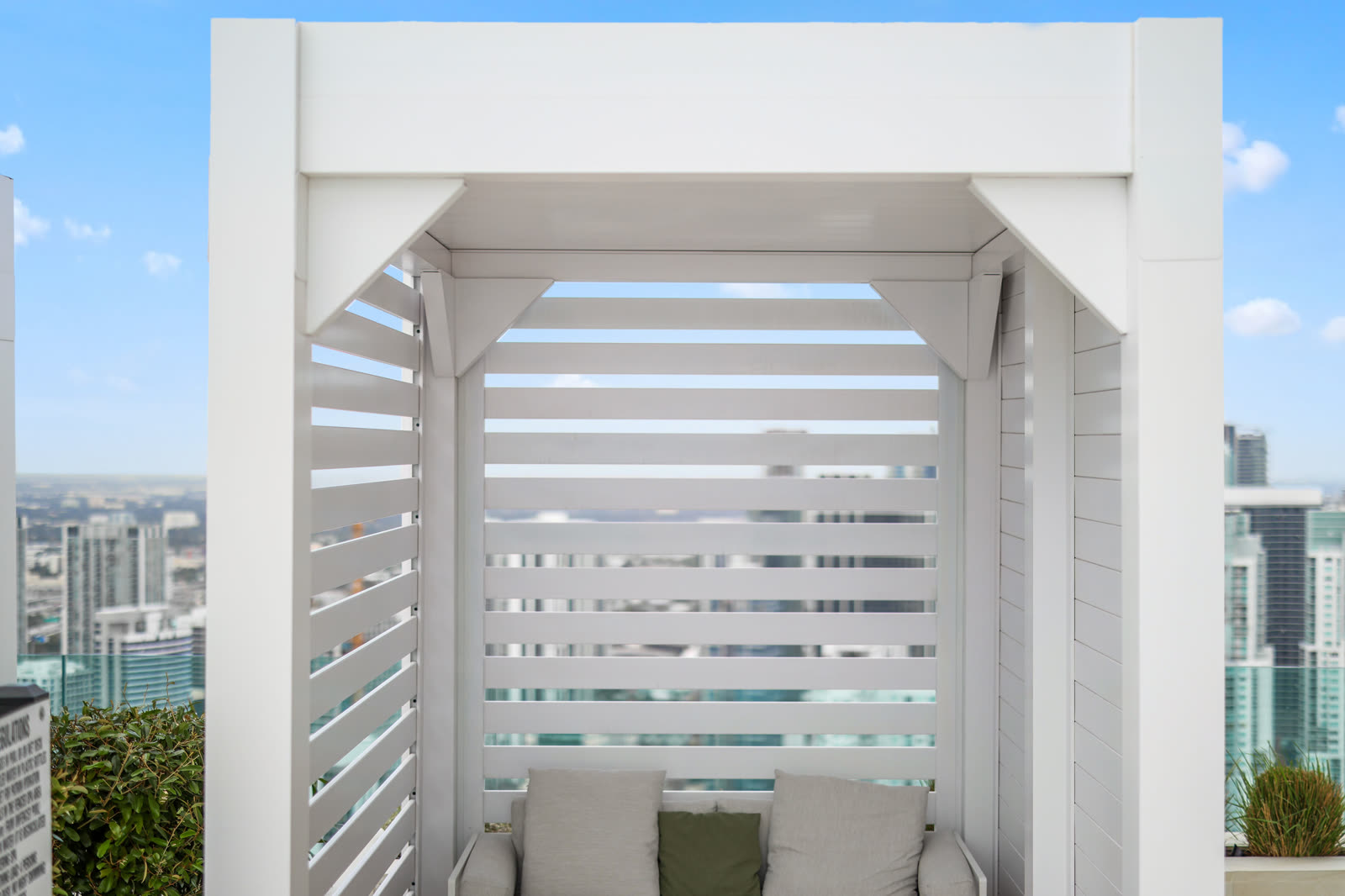 White Azenco R-BLADE louvered pergola over a resort-style pool deck with privacy wall &mdash; the same configuration Austin HOAs specify for shaded lounge zones adjacent to the clubhouse.