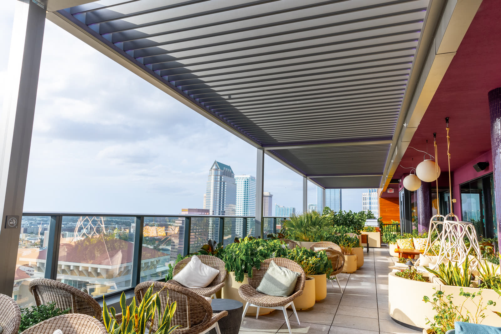 Gray Azenco R-BLADE on a commercial rooftop restaurant patio &mdash; alternate angle showing engineered anchoring and the concealed gutter system.