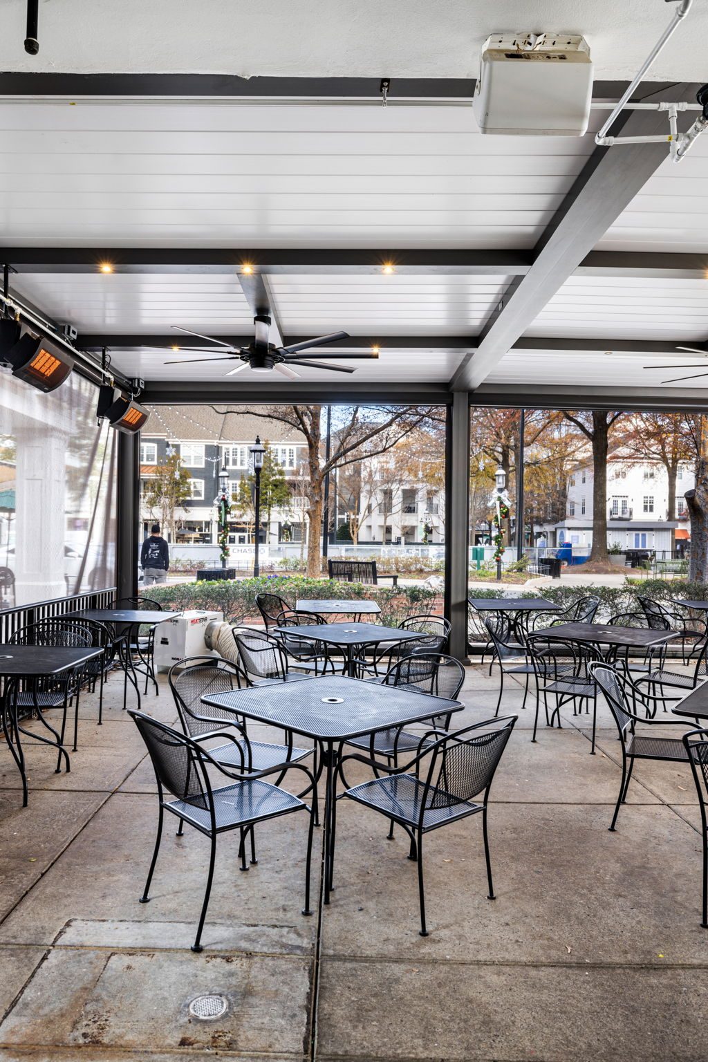Gray bronze R-BLADE commercial pergola with white louvers, ceiling fans, recessed lights and heaters over a restaurant patio
